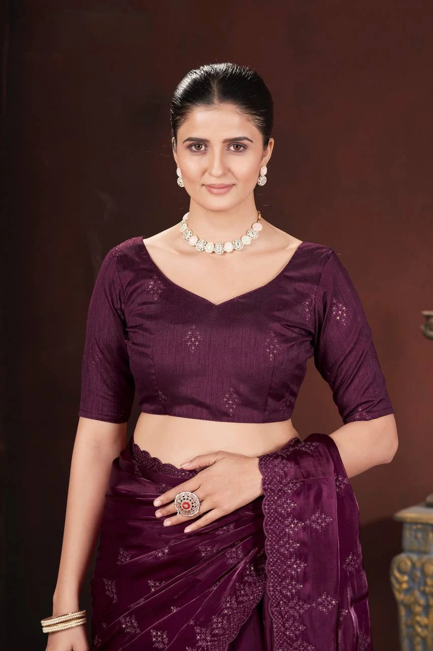 Woman wearing a purple saree with a matching blouse against a dark background